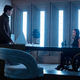 Brenton Thwaites as Dick Grayson stands in front of Savannah Welch as Barbara Gordon behind a desk and in a wheelchair in Titans season 3 for HBO Max.